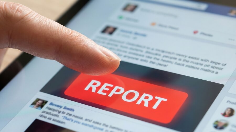 Hand pressing a red report button on a social media interface